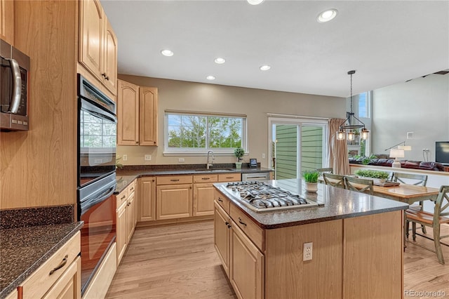 kitchen with appliances with stainless steel finishes, a sink, light wood finished floors, and light brown cabinets