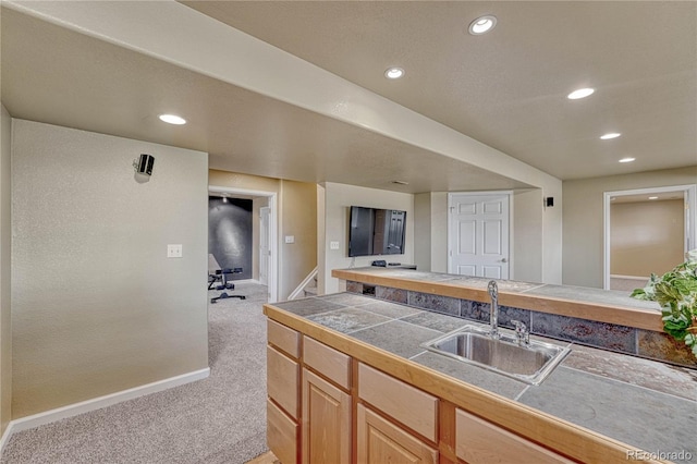 kitchen with carpet floors, recessed lighting, baseboards, and a sink