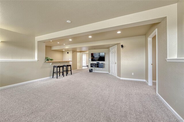 living room with carpet floors, recessed lighting, baseboards, and a textured wall