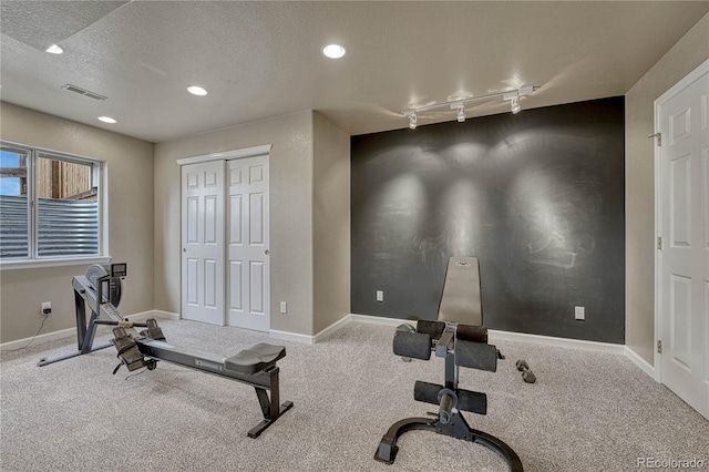 exercise room featuring track lighting, baseboards, carpet, and visible vents