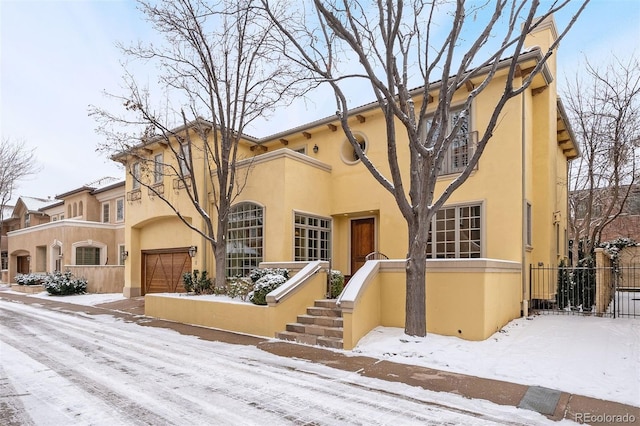 view of front of house with a garage, fence, and stucco siding