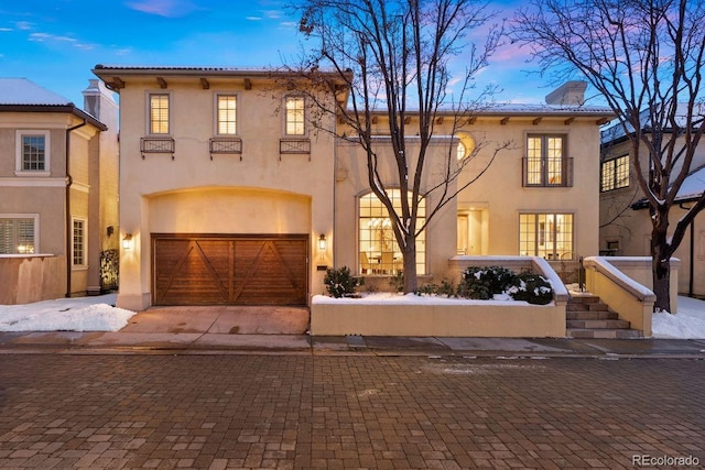 mediterranean / spanish-style house with driveway, an attached garage, a chimney, and stucco siding