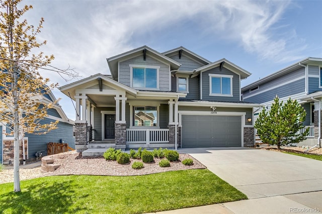 craftsman inspired home with covered porch, driveway, stone siding, a garage, and a front yard