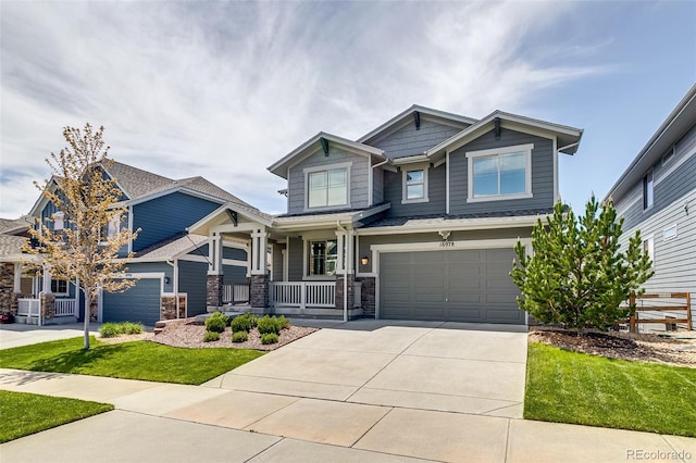 craftsman house featuring a porch, driveway, a garage, stone siding, and a front yard