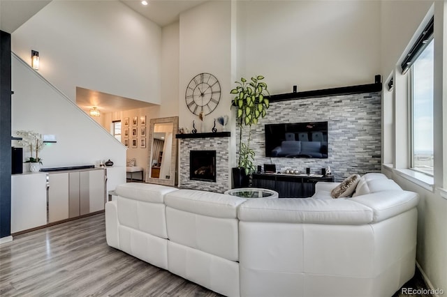living room with a high ceiling, wood finished floors, and a fireplace