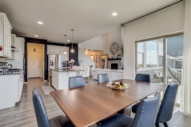 dining room with a fireplace, light wood finished floors, and recessed lighting