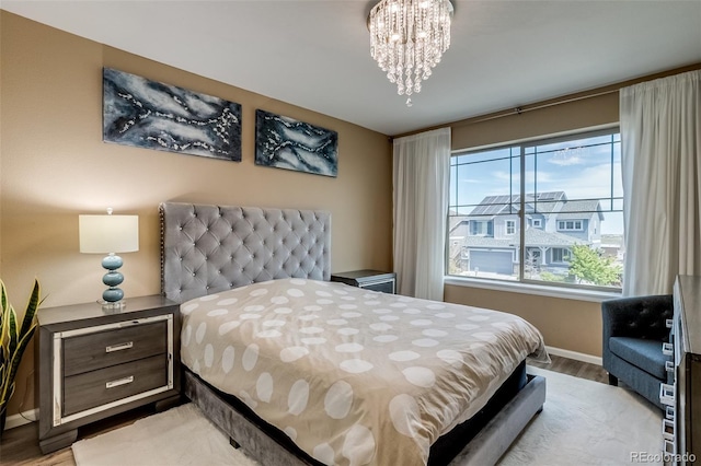 bedroom featuring light wood-style flooring, a chandelier, and baseboards