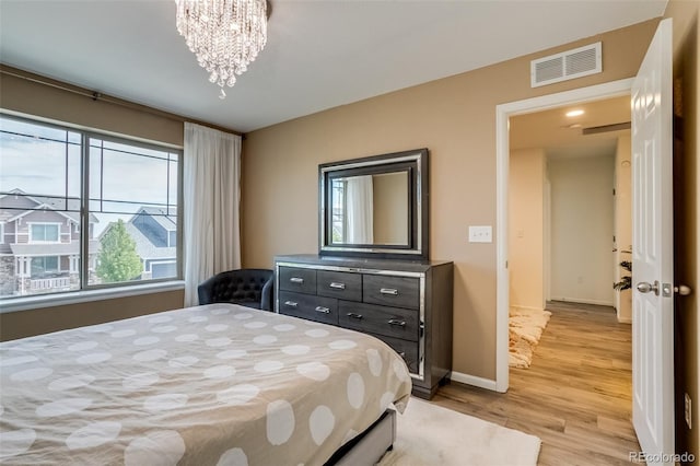 bedroom with light wood-style floors, multiple windows, a chandelier, and baseboards