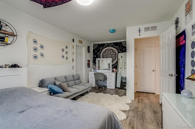 bedroom featuring light wood finished floors and an office area