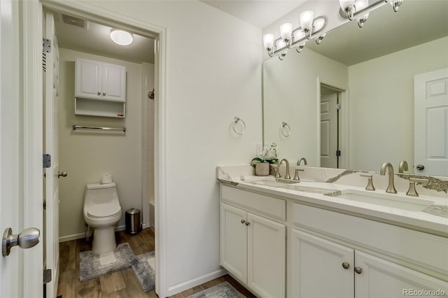 full bathroom with wood finished floors, toilet, double vanity, and baseboards