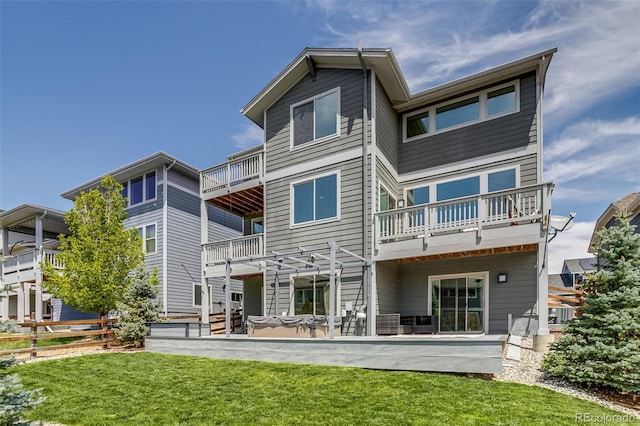 rear view of property with a balcony, a lawn, and a patio area