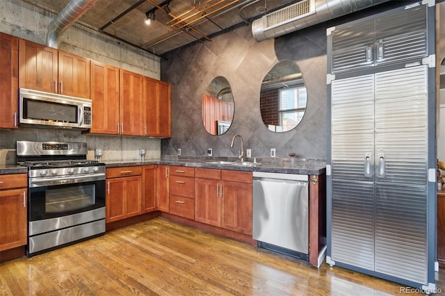 1720 Wazee St Unit 2B, Denver, CO 80202 - kitchen featuring appliances with stainless steel finishes, light wood-type flooring, brown cabinets, and backsplash