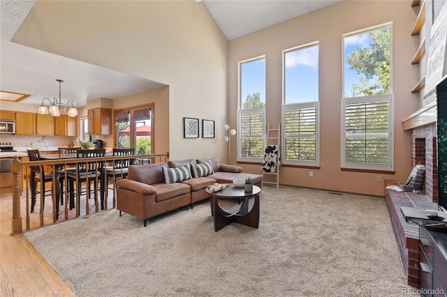 9447 Chesapeake St, Highlands Ranch, CO 80126 - living area featuring a towering ceiling, a chandelier, a brick fireplace, and light wood-style flooring