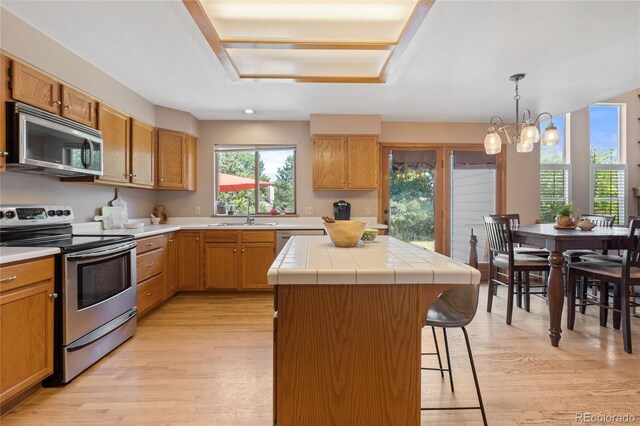 9447 Chesapeake St, Highlands Ranch, CO 80126 - kitchen with stainless steel appliances, light wood-type flooring, a center island, a breakfast bar area, and a chandelier