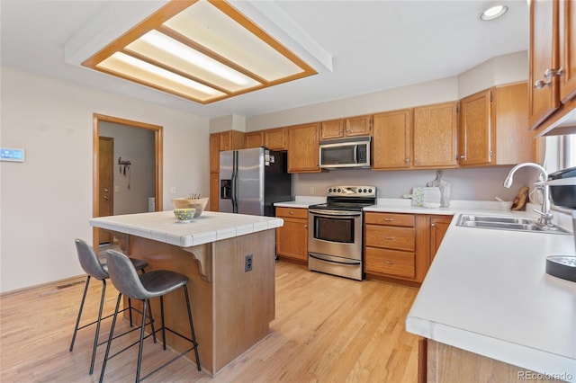 9447 Chesapeake St, Highlands Ranch, CO 80126 - kitchen featuring stainless steel appliances, a kitchen island, a breakfast bar area, light wood-style floors, and recessed lighting
