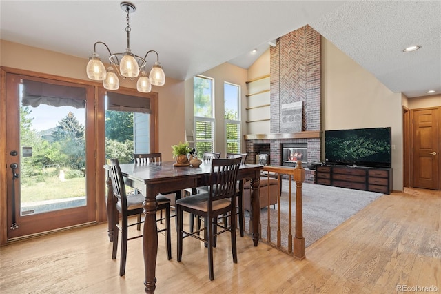 9447 Chesapeake St, Highlands Ranch, CO 80126 - dining room featuring lofted ceiling, light wood-style flooring, a brick fireplace, and a chandelier