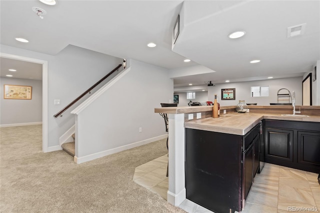 9447 Chesapeake St, Highlands Ranch, CO 80126 - kitchen featuring dark cabinetry, light colored carpet, light countertops, recessed lighting, and a kitchen bar