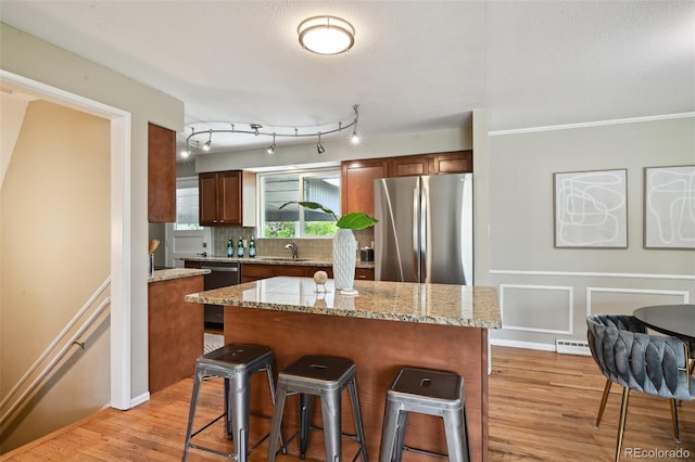 1646 S Stuart St, Denver, CO 80219 - kitchen featuring freestanding refrigerator, light wood-style floors, a kitchen bar, a sink, and tasteful backsplash