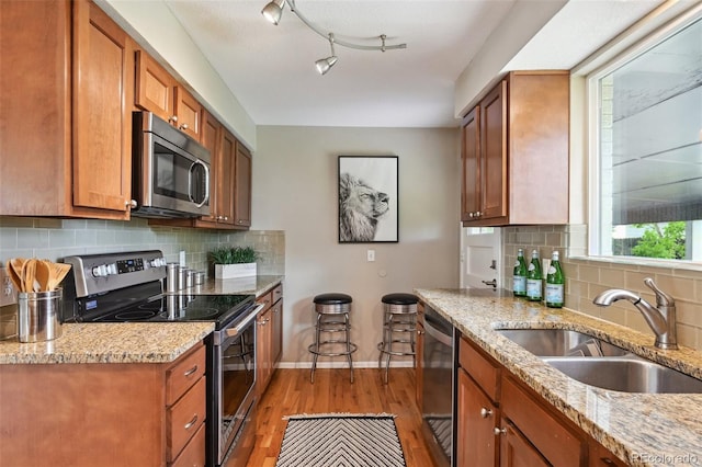 1646 S Stuart St, Denver, CO 80219 - kitchen with appliances with stainless steel finishes, a sink, light wood-style flooring, and brown cabinetry