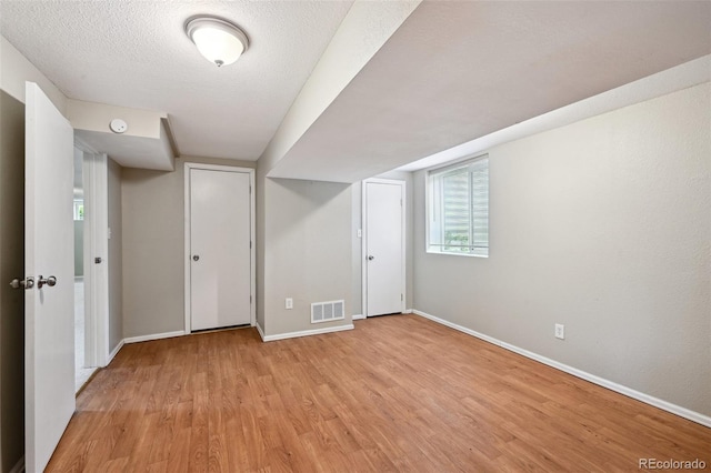 1646 S Stuart St, Denver, CO 80219 - below grade area featuring baseboards, light wood finished floors, and a textured ceiling
