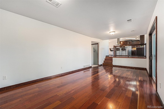 living area with visible vents, dark wood finished floors, stairway, and baseboards