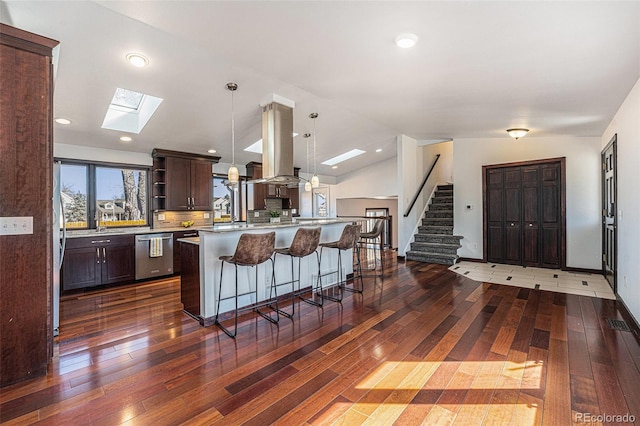 kitchen with a kitchen breakfast bar, dark brown cabinets, appliances with stainless steel finishes, open shelves, and lofted ceiling with skylight