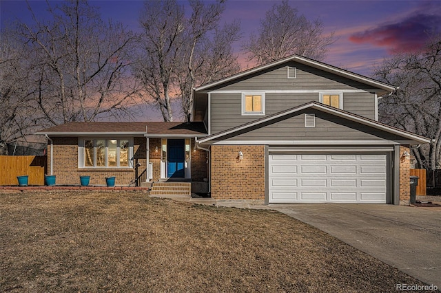 split level home with brick siding, driveway, and fence