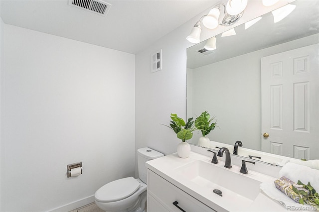 half bath with toilet, baseboards, visible vents, and vanity