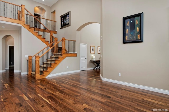 14022 E Fair Pl, Centennial, CO 80111 - unfurnished living room featuring wood finished floors, a high ceiling, arched walkways, baseboards, and stairs