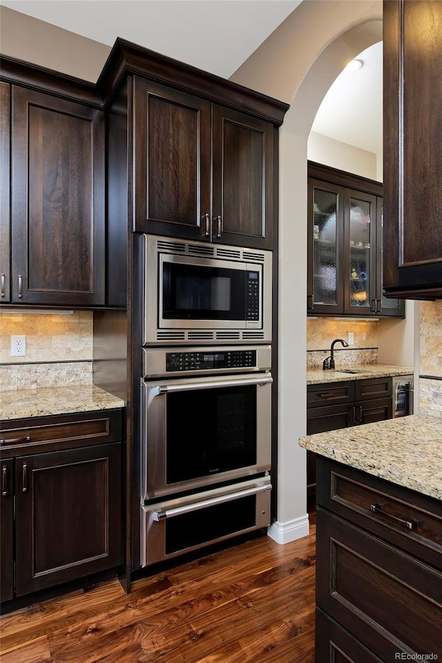 14022 E Fair Pl, Centennial, CO 80111 - kitchen with stainless steel appliances, arched walkways, dark brown cabinetry, and backsplash