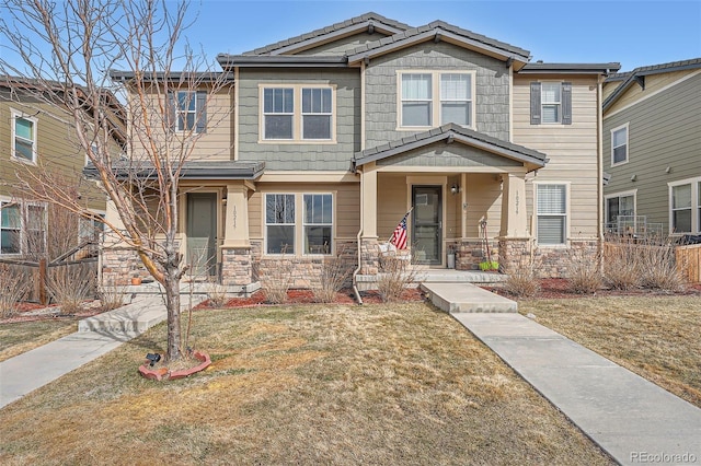 craftsman-style home featuring a front yard, covered porch, and stone siding