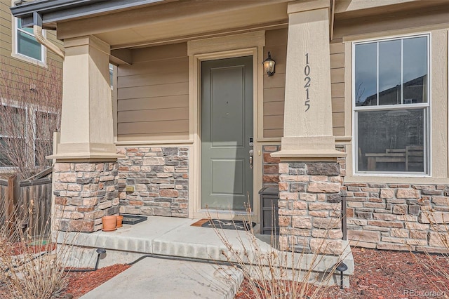 entrance to property with a porch and stone siding