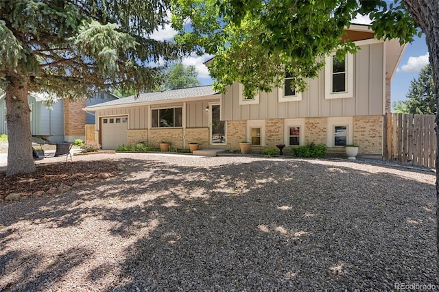 4589 S Sleepy Hollow Cir, Colorado Springs, CO 80917 - split level home with brick siding, an attached garage, board and batten siding, and gravel driveway