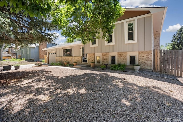 4589 S Sleepy Hollow Cir, Colorado Springs, CO 80917 - split level home with brick siding, board and batten siding, a garage, and gravel driveway
