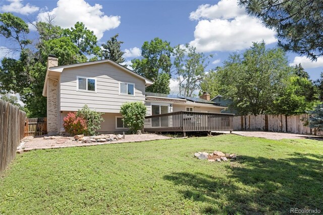 4589 S Sleepy Hollow Cir, Colorado Springs, CO 80917 - rear view of house featuring a wooden deck, a fenced backyard, a chimney, and solar panels