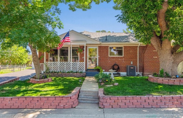1922 Graves Ct, Northglenn, CO 80233 - view of front of home featuring brick siding, a front lawn, roof with shingles, and a sunroom