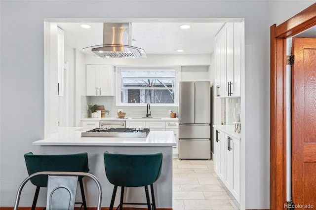 kitchen featuring backsplash, sink, white cabinetry, island exhaust hood, and stainless steel appliances