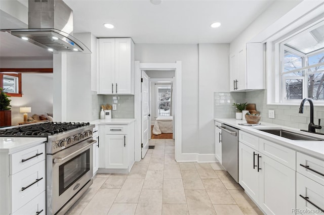 kitchen with decorative backsplash, stainless steel appliances, sink, wall chimney range hood, and white cabinetry