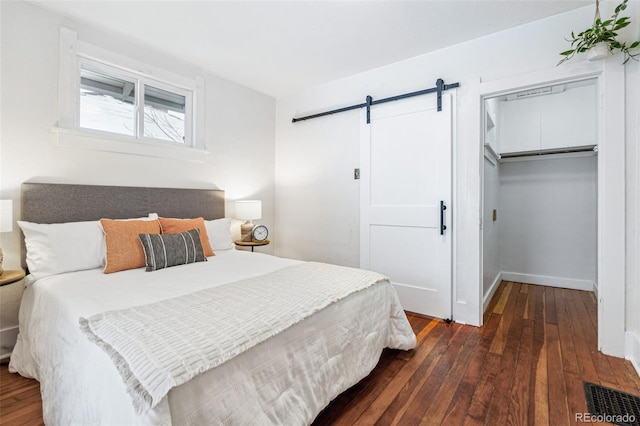 bedroom featuring a barn door, a closet, and dark wood-type flooring