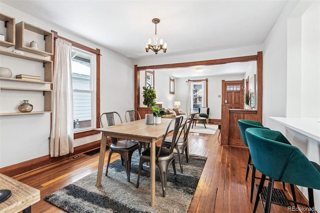 dining area with hardwood / wood-style flooring and an inviting chandelier