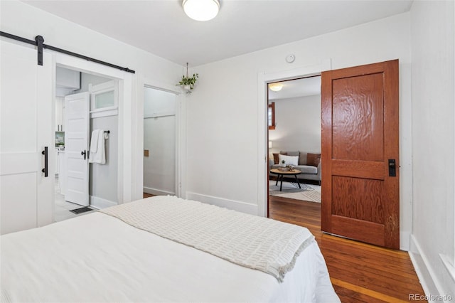 bedroom with a barn door and wood-type flooring