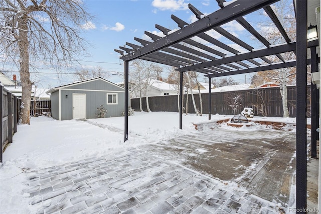 snow covered patio featuring a pergola and an outbuilding