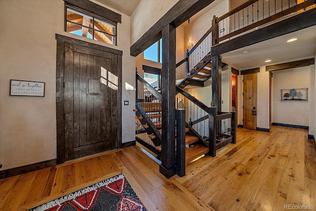 entryway with light wood-type flooring, a wealth of natural light, and a high ceiling