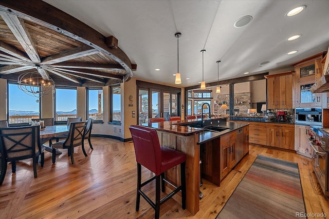 kitchen with a center island with sink, tasteful backsplash, a chandelier, pendant lighting, and sink