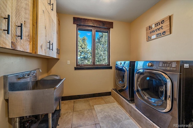 washroom featuring light tile patterned flooring, sink, washing machine and clothes dryer, and cabinets