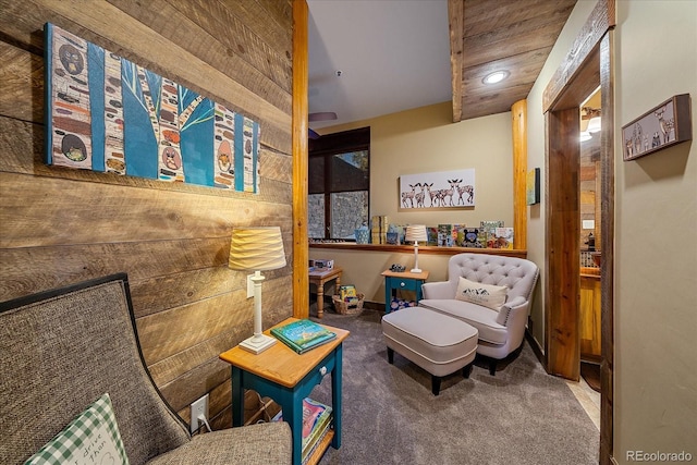 living area with wooden ceiling, carpet flooring, and wooden walls