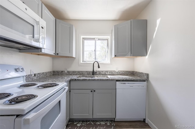 6600 E 76th Pl, Commerce City, CO 80022 - kitchen with gray cabinetry, white appliances, dark wood finished floors, light stone counters, and a sink