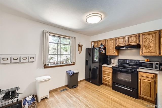 800 Illinois St Unit 1, Golden, CO 80401 - kitchen with black appliances, under cabinet range hood, light countertops, light wood-style flooring, and brown cabinets