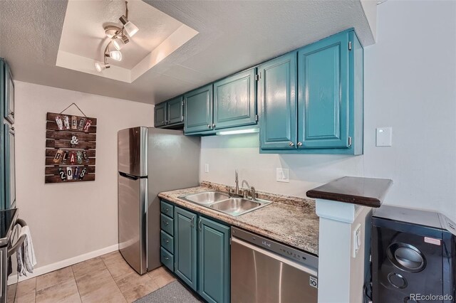 kitchen with a raised ceiling, sink, light tile patterned floors, stainless steel appliances, and blue cabinetry