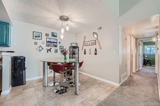 dining space featuring light carpet and a textured ceiling